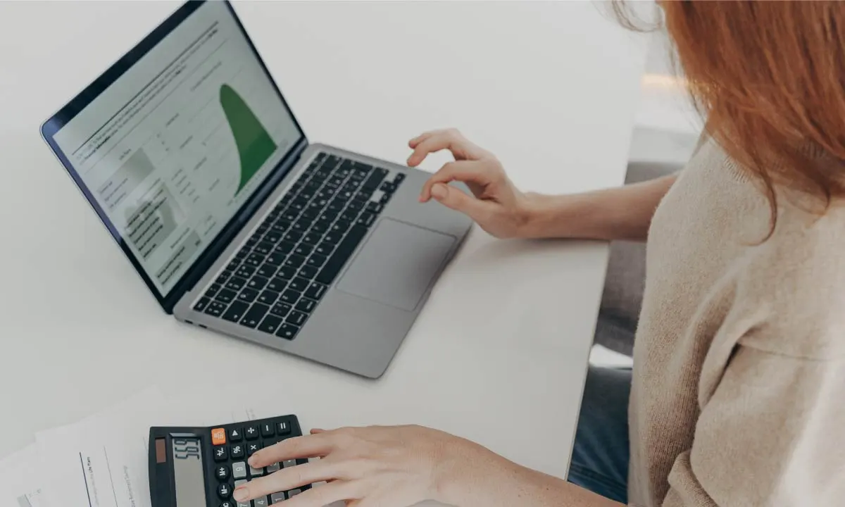 Woman doing financials on laptop and calculator